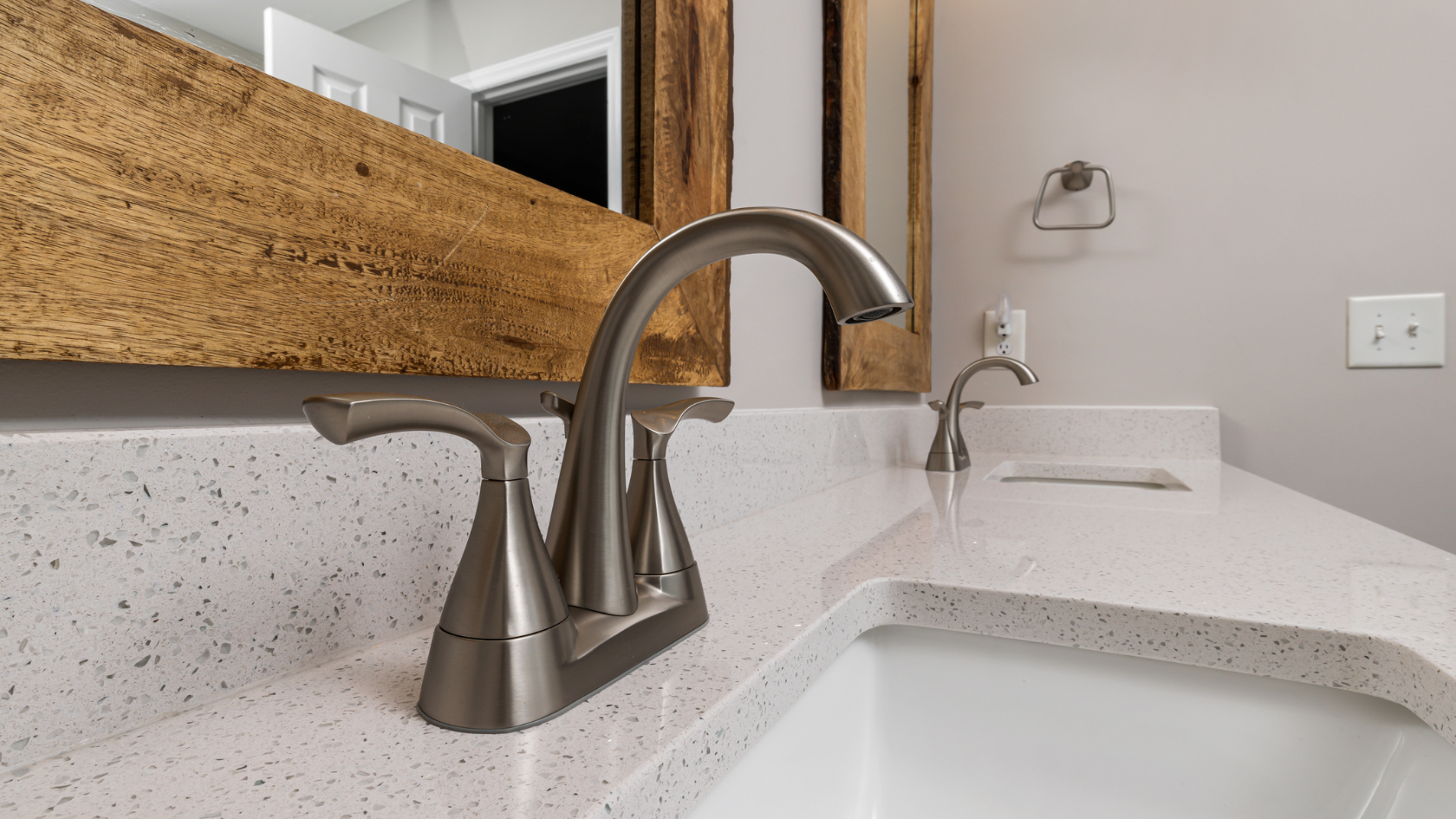 A bathroom sink with a wooden mirror above it